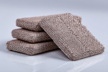 Poster - A stack of three rough textured jute burlap cloths, showcasing natural fiber design, in neutral tones, on a white surface, macro shot, soft light, elegance.