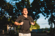 © Mdv Edwards - Middle aged Southeast Asian man runs through park wearing weighted backpack, regulating his breathing during an intense rucking workout. VO2 max run.