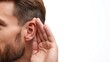 © Elena - Closeup of a young man with a beard listening intently, cupping his ear against a bright white background, exuding curiosity and attentiveness with copy space on the left
