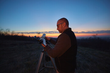 Wall Mural - amateur astronomer using telescope and smartphone for watching stars, moon, planets and other celest