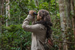© Gino Tuesta - Female explorer birdwatching in the Amazon rainforest, using a binoculars