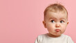 © Ekaterina - Curious baby with a puzzled expression frowns slightly while looking up, set against a pink background, capturing a moment of innocent confusion.