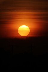 Wall Mural - golden evening sun dips below the city skyline, casting a warm orange glow across the tranquil river