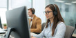© Qrryferry - Customer service representative wearing headset working computer in modern office environment