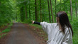 © SlepoyKot - A young woman in a light beige hoodie in the forest pointing toward the road