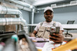 © fotofabrika - Skilled worker checking smartphone while seated in a modern workspace with exposed ductwork