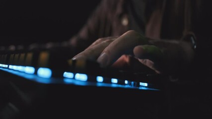 Close-up: a gamer's hand on a colored keyboard. The player's fingers press the movement buttons. Computer video game championship for all ages. An online tournament on modern sports.