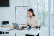 © PSG - Image of beautiful Asian woman sitting and working with laptop, documents, graphs in office.
