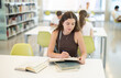 © JackF - Young woman student reading textbooks and taking notes at table in library