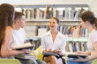 © JackF - Group of students reading and discussing books while sitting on chair in library