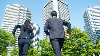 Poster - 新緑の都市を走る男女ビジネスパーソンの後ろ姿