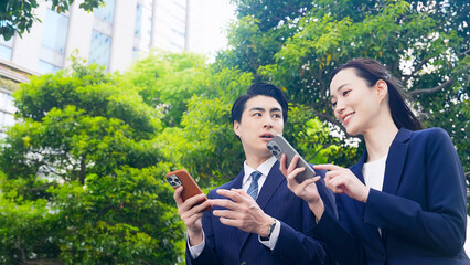 Poster - 新緑の街でスマホを使う男女ビジネスパーソン