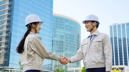 Poster - 建設現場で握手する男女エンジニアのグループ