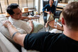 © Jovo Jovanovic/Stocksy - Happy gay couple talking while sitting on sofa in therapy center