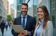 © Vadym - Smiling business partners, man woman pose near office building. Corporate teamwork, partnership, success. Male, female executives looking camera. City, urban background, business lifestyle.