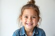 © Vadym - Portrait of happy, smiling child girl. Cute young female with beautiful brown eyes and hair bun. Caucasian kid in casual denim clothes. Positive emotions. White background, copy space.