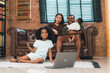 © chokniti - Heartwarming family moment as an African American father and daughter share playful time together on the couch, surrounded by love, laughter, and the warmth of home, while mom gently looks on with joy