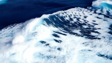 Poster - Crashing wave of turbulent ocean water creates white foam and patterns on a blue sea surface, view from above captures the energy of the ocean.