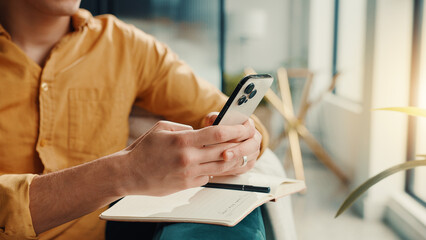 Aufkleber - Phone, notebook and hands of man in home for finance journal, planning or investment information. Cellphone, diary and male person with research for online banking on mobile app in apartment.
