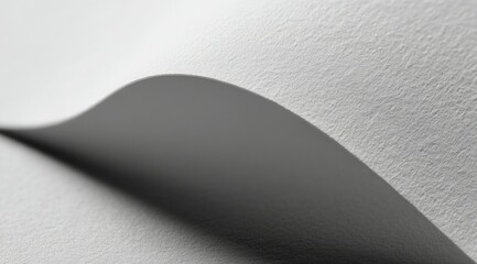 Poster - A grayscale close-up showcases a subtly curved sheet of textured paper, its gentle undulation casting a soft shadow, creating depth and highlighting the paper's surface texture