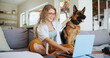 © peopleimages.com - Laptop, smile and dog with woman on sofa for pet insurance research, premium benefits and online. Animal policy cover, typing and application with person and german shepherd at home for vet claims