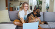 © peopleimages.com - Laptop, online and dog with woman on sofa for pet insurance research, premium benefits and reading. Animal policy cover, typing and application with person and german shepherd at home for vet claims