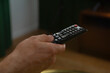 © Danil Nevsky/Stocksy - Hand holding remote control, changing channels on television