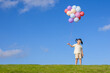 © mei - A little girl is playing with a balloon on the grass under the blue sky and white clouds