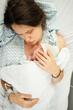 © Artem Zhushman/Stocksy - Newborn cradled by mother in hospital setting