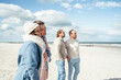 © Westend61 - Group of adult friends standing and talking on coastal beach