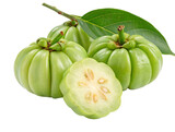 Close up of several garcinia cambogia fruits with one cut open on a white surface and green leaf near by