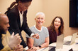 © Johnér - Smiling short haired entrepreneur sitting with colleagues in meeting room at office