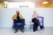 © Johnér - Female entrepreneur discussing ideas with male coworker while sitting on armchair in office