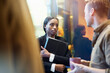 © Johnér - Female business professional holding laptop talking with male colleague in office