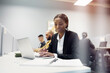 © Johnér - Young female business professional working on laptop while reading details in diary at office