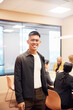 © Johnér - Portrait of smiling businessman wearing eyeglasses standing with hand in pocket at office board room