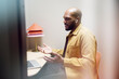 © Johnér - Bald male entrepreneur wearing wireless in-ear headphones talking on video call through laptop in office