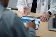 © NINENII - Close up of aged man patient hand signing medical insurance contract at doctor office.