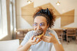 © Dusan Petkovic - Portrait of hungry multicultural girl sitting in fast food restaurant, biting and eating delicious doughnut.