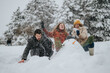 © qunica.com - Three joyful friends engaged in a fun snowball fight and constructing a snowman surrounded by a picturesque snowy forest, capturing the essence of winter leisure and camaraderie outdoors.
