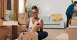 © ABCreative - A girl with glasses sits in the middle of her new flat, unpacking belongings. She holds a vase and smiles into the lens, while the man in the background continues cleaning the space.