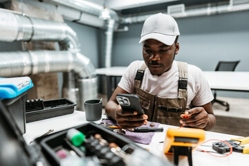 Poster - Technician working on a smartphone while seated at a desk in a modern workspace during daytime