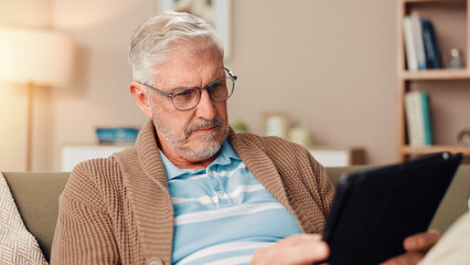 Poster - Senior man, tablet or reading with glasses on sofa for ebook, knowledge or online news at home. Mature, male person or pensioner with technology on couch for research, story or digital novel at house