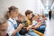 © leszekglasner - School youth in the corridor use smartphones and social media en masse, internet addiction in children