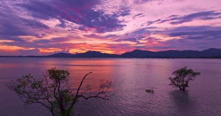 Wall Mural - Aerial view of A tranquil sunset over a calm coastal landscape, with colorful sunset behind distant mountains and reflecting on the sea.The serene water create a peaceful and atmospheric view