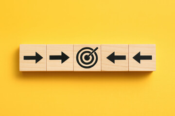 Poster - Success and focus are symbolized by wooden arrows converging toward a central target against a bright yellow background illustrating goal alignment in business strategy