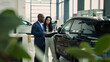 © wedmoments.stock - African-American car salesman signs a contract with a woman to sell a new car at a car dealership. The concept of successfully buying and selling a new car and insurance.