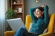 © Pete - Young smiling woman freelancer relaxing after work at home. Happy female sits in chair with laptop and looks out window dreaming. Peaceful home office, remote job, well-being.