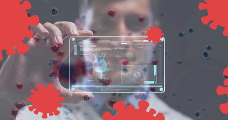 Poster - Image of covid-19 cells over caucasian male doctor holding a futuristic screen