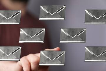 Poster - Close-up of a hand selecting a digital email from a group of metallic envelopes.